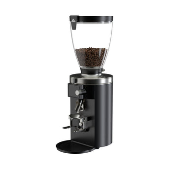 Angled view of the black Mahlkönig E65S grinder with a transparent hopper filled with coffee beans and adjustable portafilter holder.