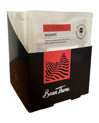 Open display box of Bean There Ethiopia Sidamo compostable drip bags with individually wrapped single serve coffee sachets visible.