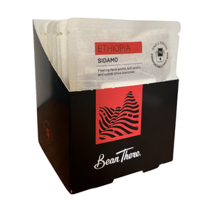 Open display box of Bean There Ethiopia Sidamo compostable drip bags with individually wrapped single serve coffee sachets visible.