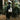 Person carrying a Bean There “Seek the Best” canvas tote bag standing near lush greenery and a signpost featuring African coffee origins